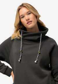 Felpa con cappuccio grigia scura a collo alto, con lacci bianchi e viola e dettagli verdi. Realizzata in un tessuto morbido e testurizzato.