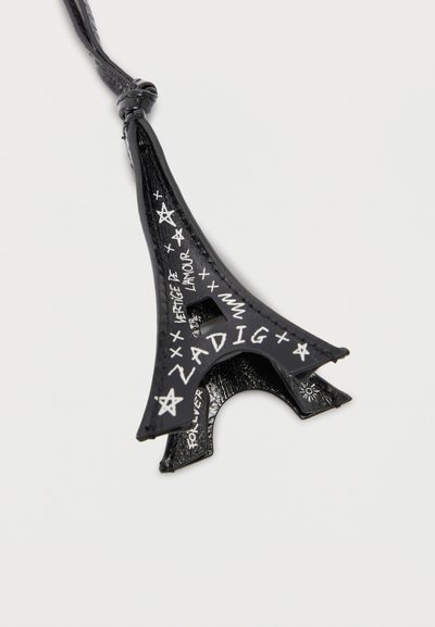 Μπρελόκ από μαύρο δέρμα με το κέντρο του Πύργου του Άιφελ, με λευκά χειρόγραφα γράμματα "Ζαντίγκ", "L'amour", αστέρια και διακοσμητικά σύμβολα σε λευκό φόντο.