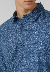 Niebieska koszula w kwiaty z guzikami, z kołnierzykiem i teksturowaną tkaniną. Charakteryzuje się nowoczesnym fasonem i dopasowanym krojem.