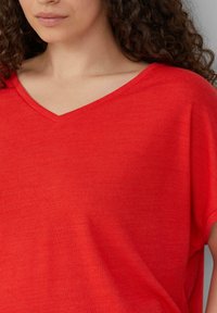 Rode V-hals T-shirt met een losse pasvorm, gemaakt van een zachte, gestructureerde stof, met korte mouwen en een subtiel gemêleerd patroon.