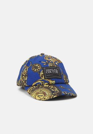 Casquette de baseball bleue avec des motifs dorés ornés et un patch noir portant l'inscription "Versace Jeans Couture" sur le devant.