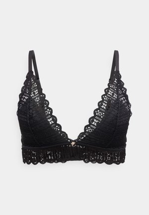Bralette en dentelle noire avec bords festonnés, bretelles réglables et un petit charm décoratif au centre de la bande avant.