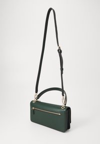 Green leather crossbody bag with a detachable strap, zippered pocket on the front, and smooth texture. Compact rectangular design.