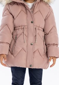 Veste doudoune rose avec une capuche en fourrure, matelassage en losanges, deux poches zippées sur les côtés, taille ajustable avec cordon, et boutons-pression.