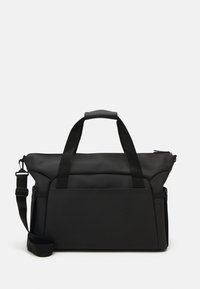 Sac fourre-tout noir avec une texture lisse, doté de doubles poignées, d'une bandoulière amovible et d'une poche avant. Fermeture zippée en haut.
