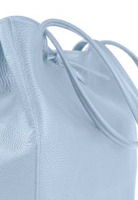 Sac à main en cuir bleu clair avec une finition texturée, doté de longues anses arrondies et d'un design ouvert sur le dessus.