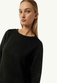 Czarna bluza z teksturowanym geometrycznym wzorem, okrągłym dekoltem i długimi rękawami. Wykonana z miękkiego, prążkowanego materiału dla większego komfortu.
