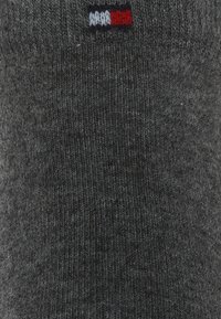 Grau knee-length Socke aus einem weichen, strukturierten Material. Verfügt über einen kleinen Logopatch mit roten, weißen und blauen Akzenten nahe der Oberkante.