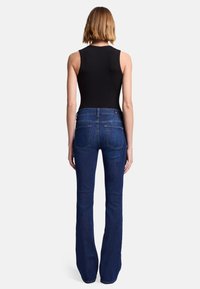 Jeans blu a zampa d'elefante con lavaggio medio e design a cinque tasche. Il tessuto è denim, con cuciture sottili e una vestibilità classica.