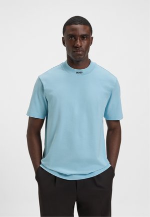 Lyseblå bomulds T-shirt, korte ærmer, rund hals med sort "BOSS" logo ved kraven. Glat tekstur, afslappet pasform.