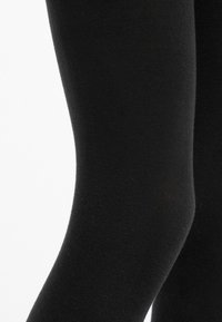 Leggings neri realizzati in tessuto morbido e elasticizzato, con un design aderente che si adatta alla forma della gamba.
