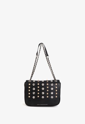 Sac à bandoulière noir avec une chaîne argentée, décoré de clous dorés et argentés disposés en rangées, logo Lola Casademunt à l'avant.