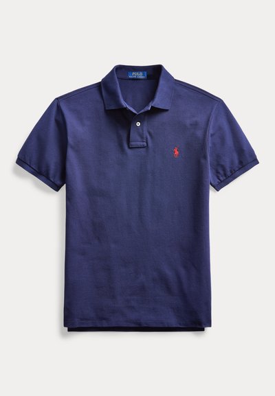 Tumesinine lühikeste varrukatega polo-särk, krae, kaks nööpi ja väike punane tikitud logo vasakul rinnal.