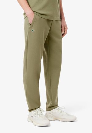 Jasnozielone, lekkie dresy z elastycznym paskiem w talii i bocznymi kieszeniami, mające małe, haftowane logo. Połączone z białymi trampkami.