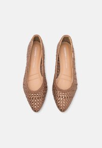 Bailarinas tejidas en marrón con punta afilada, que presentan un diseño texturizado y un interior suave. Sutil logo de la marca visible en la plantilla.