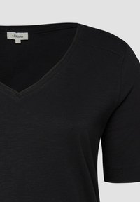 T-shirt noir à manches courtes avec col en V et une petite étiquette blanche de la marque s.Oliver à l'arrière de l'encolure, taille 44.