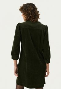 Dunkelgrünes Cordkleid mit drei Viertel Puffärmeln, einem Reverskragen und einer lockeren Passform, das eine vertikale Rippstruktur aufweist.