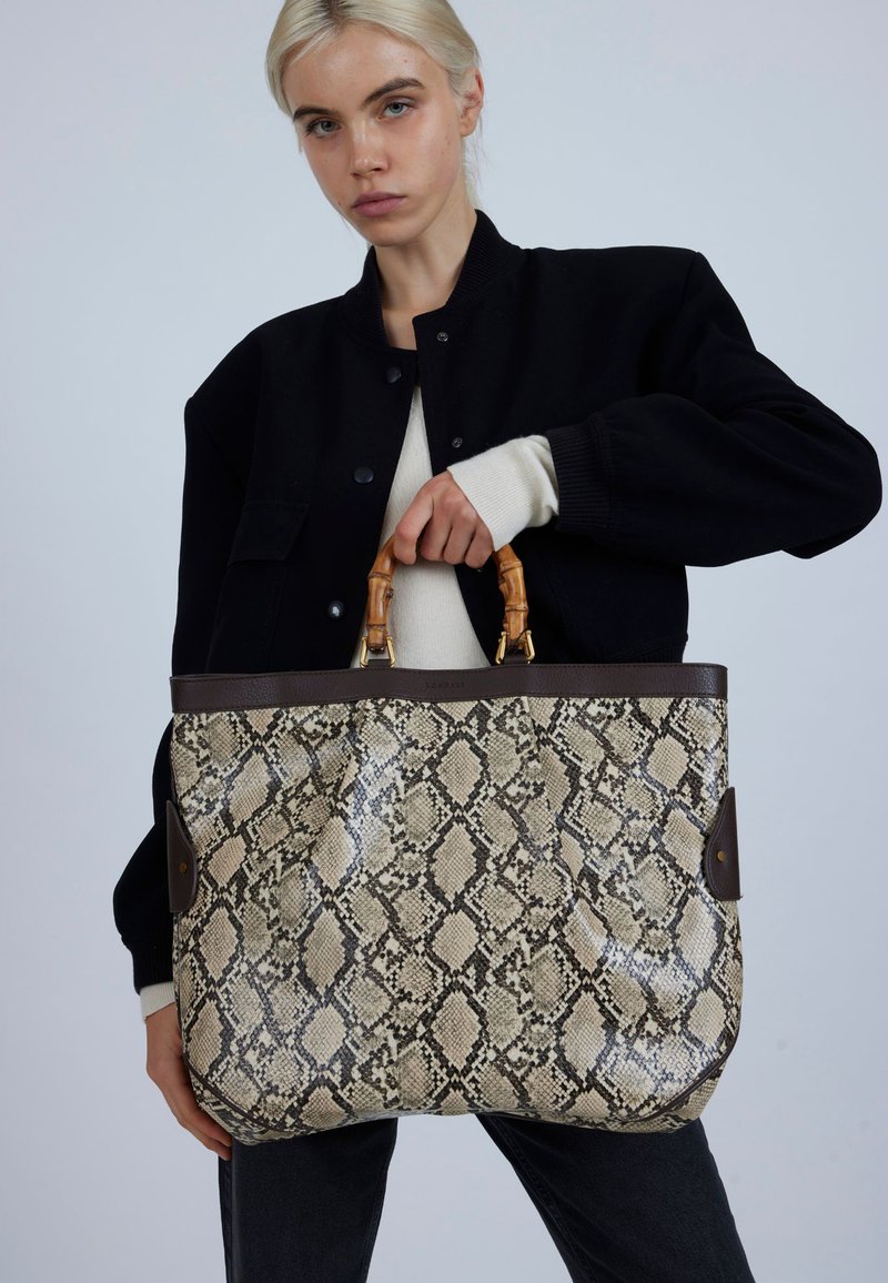 Grote boodschappentas met een nepslangenhuidpatroon, beige en bruine tinten, leren afwerking en handvatten van bamboe. Ruimtelijk en gestructureerd ontwerp.