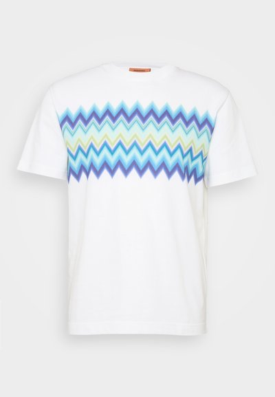 White cotton t-shirt with a zigzag pattern in blue, green, and light blue across the chest. Round neckline and short sleeves.