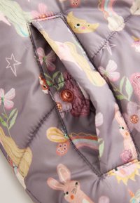 Tissu matelassé avec un bouton-pression, présentant des imprimés colorés d'animaux et de fleurs sur fond violet.