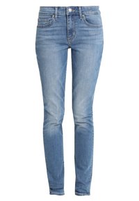 Jeans de mezclilla azul claro con corte ajustado, diseño de cinco bolsillos, detalles de desgaste sutil y cierre de botón metálico. Textura suave y color uniforme.