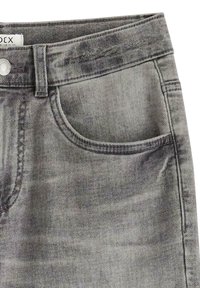 Jeans en denim gris avec une légère décoloration, un design classique à cinq poches et une fermeture à bouton en métal à la taille.