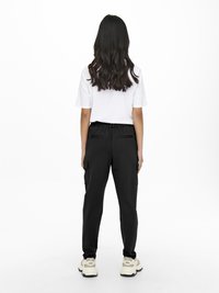 Sorte cargo bukser med elastisk talje og sidelommer, parret med en hvid t-shirt med korte ærmer, båret med beige sneakers.