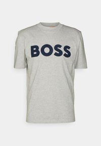 Camiseta de algodón gris con un grande logo en color marino "BOSS" en el frontal. Tiene cuello redondo y mangas cortas estándar.