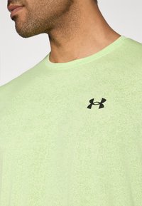 Λαχανί αθλητική μπλούζα με υφή, με μαύρο λογότυπο Under Armour στο αριστερό στήθος και στρογγυλή λαιμόκοψη.