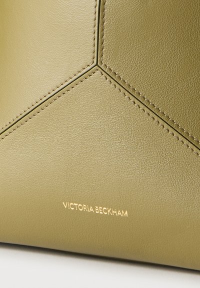 Κοντινό πλάνο τσάντας χειρός από δέρμα ελιάς με ραμμένα γεωμετρικά πάνελ και χρυσό λογότυπο "Victoria Beckham" στο κάτω κέντρο.