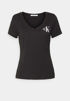 Svart bomulls t-shirt med v-ringning, korta ärmar, med en vit logotyp på vänster bröst och en rak fåll.
