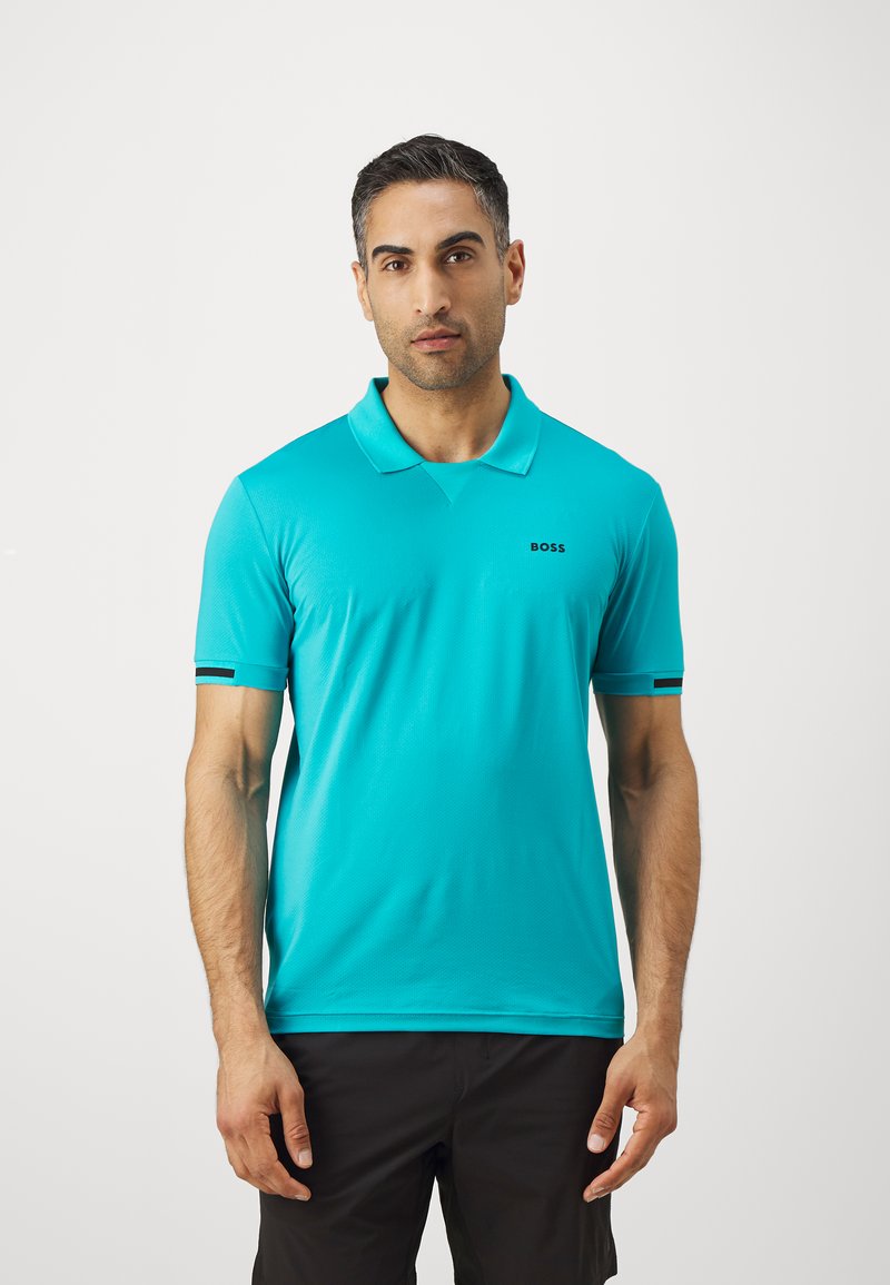 Turkizna polo majica s klasičnim ovratnikom, kratkim rukavima in črnim logotipom na prsih. Ima kontrastne poudarjene črte.
