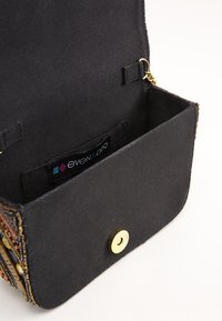 Borsa a pochette nera in tessuto con chiusura magnetica dorata e un'etichetta del marchio visibile all'interno.