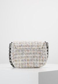 Borsa a spalla in tessuto intrecciato bianca con accenti multicolori, dotata di chiusura a pattina e tracolla in catena nera. Dettagli della superficie texture visibili.