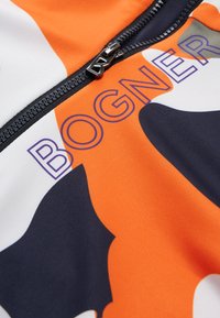 Wielokolorowy produkt marki Bogner w odcieniach pomarańczowym, granatowym, białym i szarym, z czarnym zamkiem błyskawicznym i nadrukowanym logo w kolorze fioletowym. Gładka faktura.