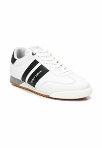 Sneaker bianca con strisce nere e branding "Teddy Smith", dotata di linguetta imbottita, suola in gomma e texture in pelle liscia.