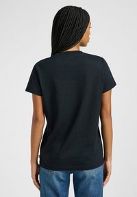 Maglietta in cotone nera a maniche corte, con scollatura rotonda e vestibilità dritta. Presenta un design minimalista, senza loghi o modelli visibili.