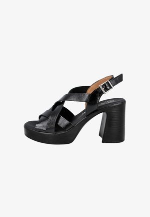 Sandalia de tacón alto de cuero negro con tiras anchas cruzadas, suela plataforma y correa ajustable con hebilla en el tobillo.