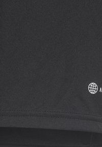 Maglietta sportiva nera, leggera e con una texture liscia. Presenta un piccolo logo con un'icona del globo in bianco sul lato inferiore.