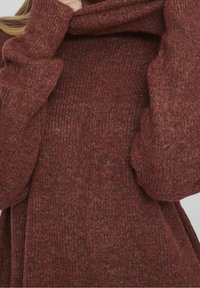 Maglione lavorato a maglia di un profondo colore ruggine, con colletto alto, maniche lunghe e una finitura morbida e testurizzata, dalla vestibilità comoda.