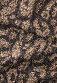 Beige og sort dyreprint stof, blød tekstur, med et fuzzy udseende og ujævne tonale variationer, der danner et dynamisk, organisk mønster.