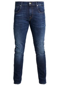 Vaqueros de mezclilla azul oscuro con ajuste slim, que presentan un sutil desgaste, diseño de cinco bolsillos, trabillas para cinturón y cierre con botón metálico.