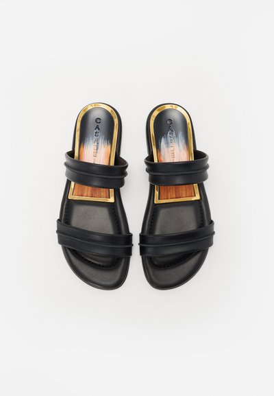 Chanclas negras sin hebilla con dos correas amplias y un acento dorado en la plantilla. La suela es acolchada con una textura suave.