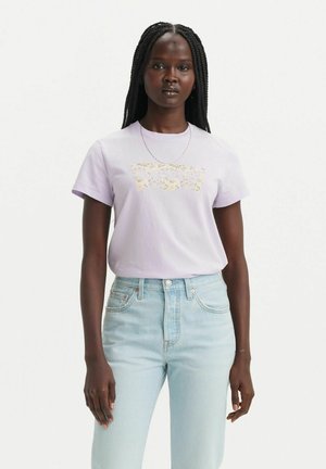 T-shirt en coton lavande à manches courtes, avec un graphique floral sur le devant. Assorti à un jean taille haute bleu clair.