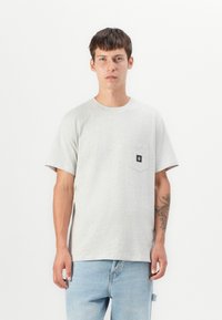 Grey short-sleeve T-shirt with a chest pocket, made from light cotton material. Features a simple, round neckline and a tag on the pocket.