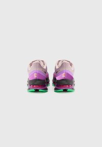 Baskets de sport en violet clair avec des accents contrastants en violet foncé et noir. Elles présentent une semelle rembourrée avec une légère semelle extérieure verte et un tige en mesh texturé.