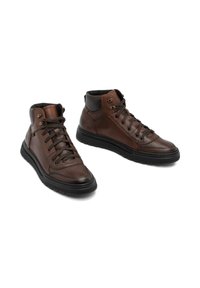 Adidași înalți din piele maro, cu sistem de prindere cu șnururi în față, guler căptușit și talpă din cauciuc negru. Prezintă ochiuri metalice și o suprafață texturată.