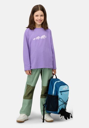 Maglietta a maniche lunghe viola con grafica di un elefante bianco, pantaloni verdi con accenti marroni e uno zaino blu con un accessorio in peluche.