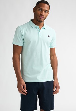 Polo bleu clair en tissu de coton avec un col classique et trois boutons. Il présente un petit logo brodé sur la poitrine.