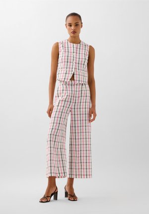 Checked two-piece outfit featuring a sleeveless cropped top with buttons and high-waisted wide-leg trousers in soft fabric.